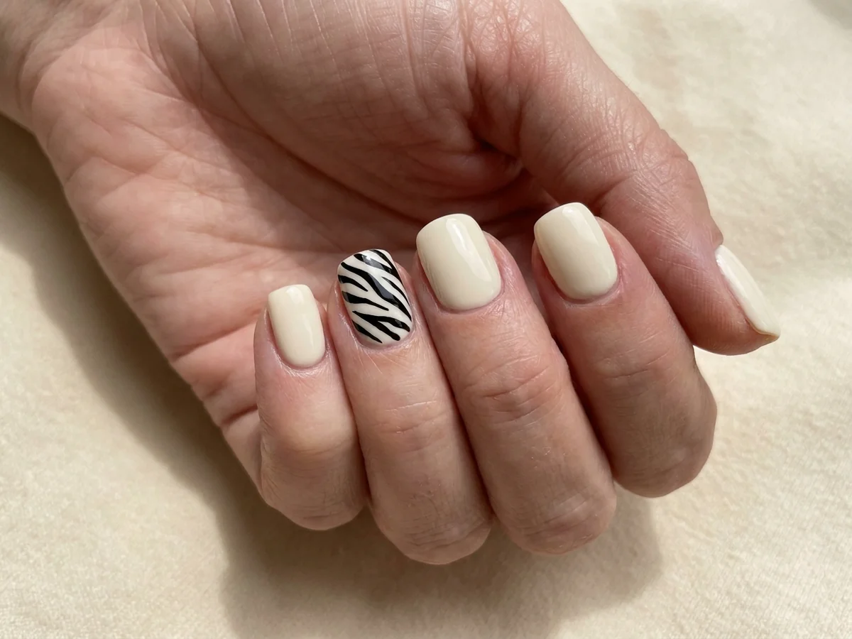 Cream manicure with tapered black zebra stripes on one accent nail