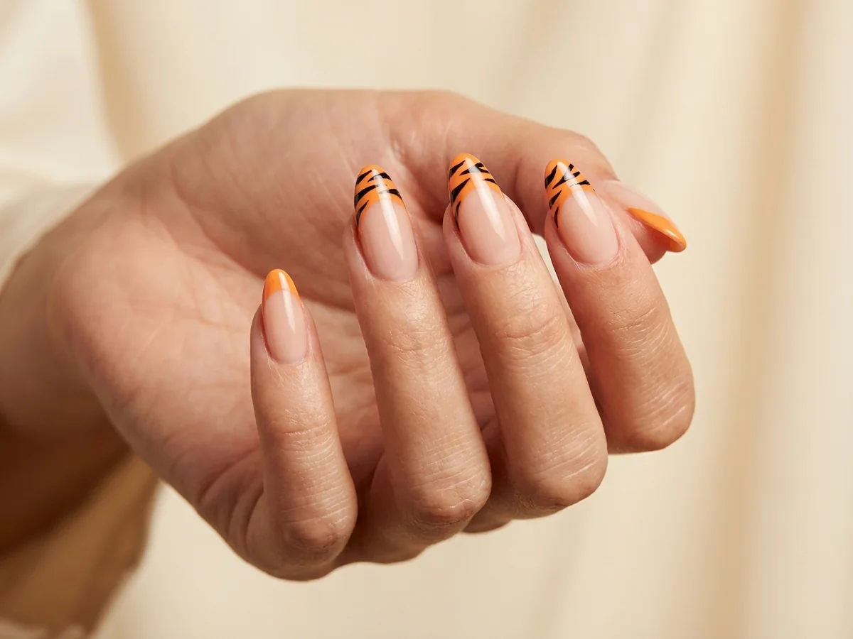 Nude nails with orange tiger-print French tips