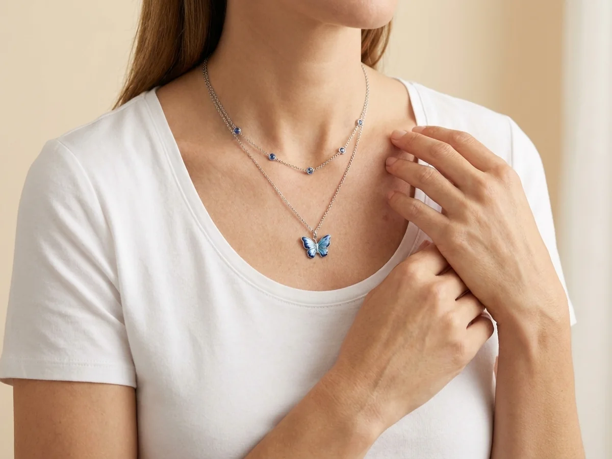 Layered blue butterfly necklace with a white scoop-neck top