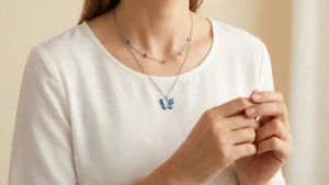 Blue butterfly pendant layered with a shorter blue-accent chain over a white blouse