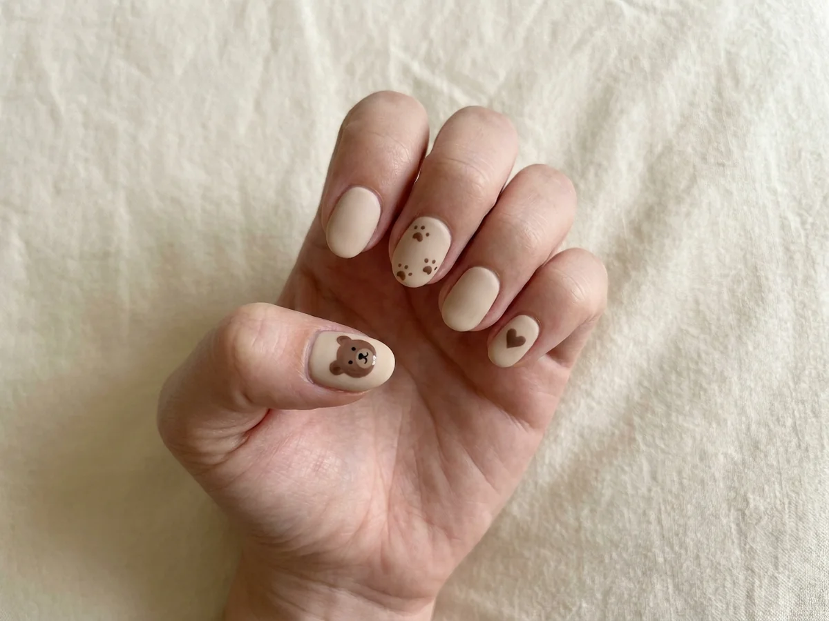 Beige manicure with a teddy-bear face, brown heart and paw print